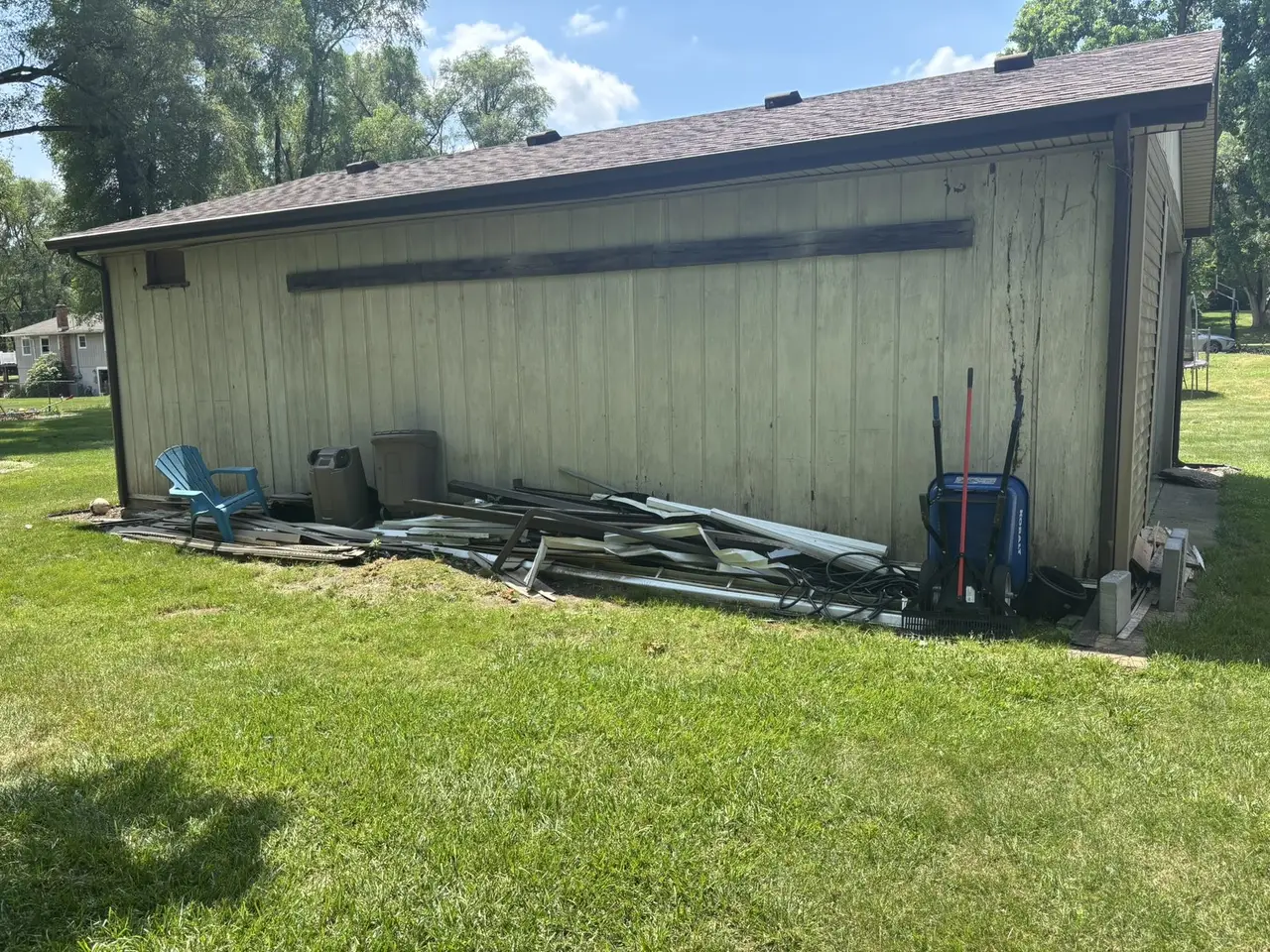 Before junk removal with debris stacked along a garage wall