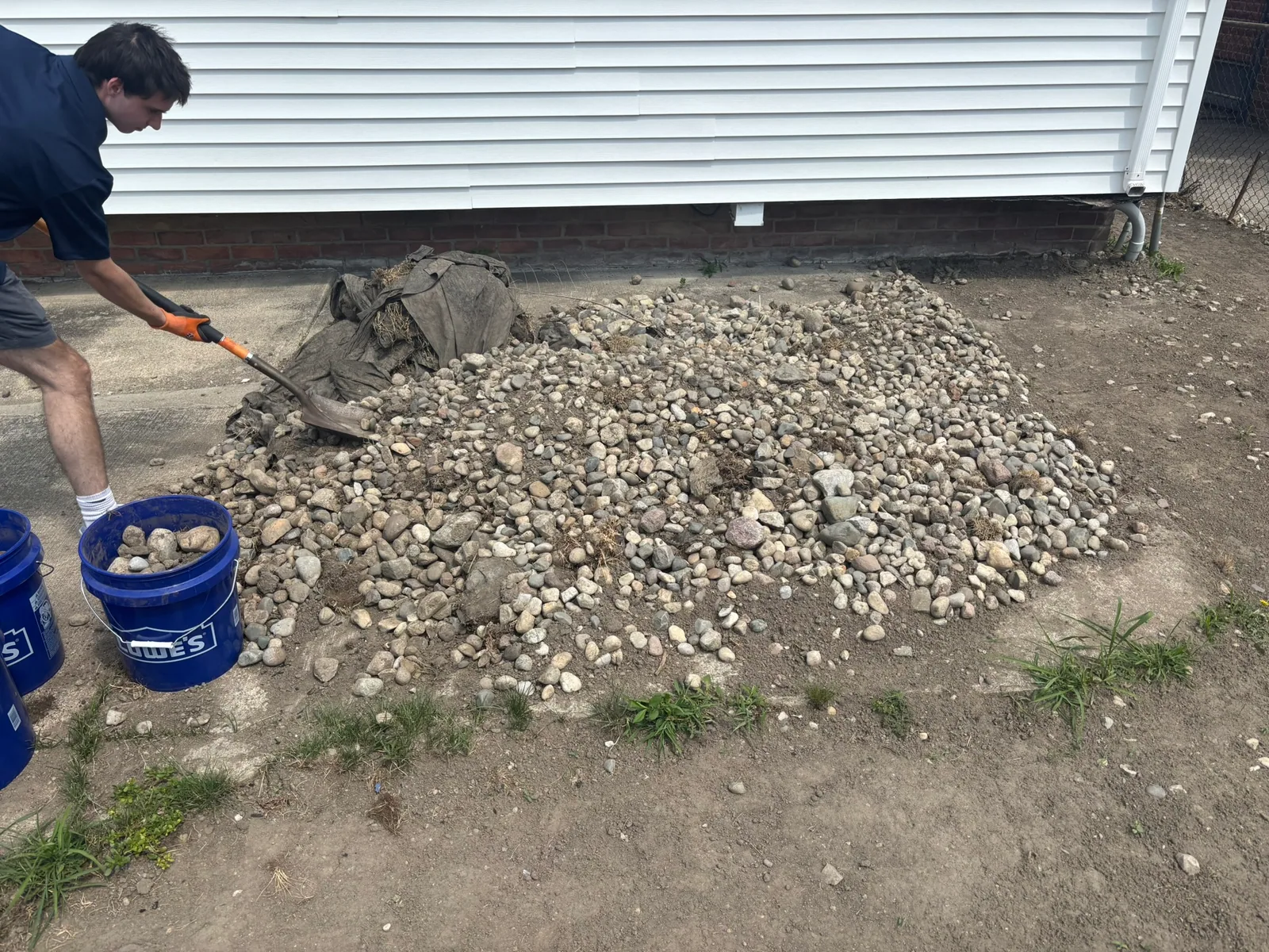 Junkernauts Junk Removal crew removing a large pile of outdoor rocks and debris